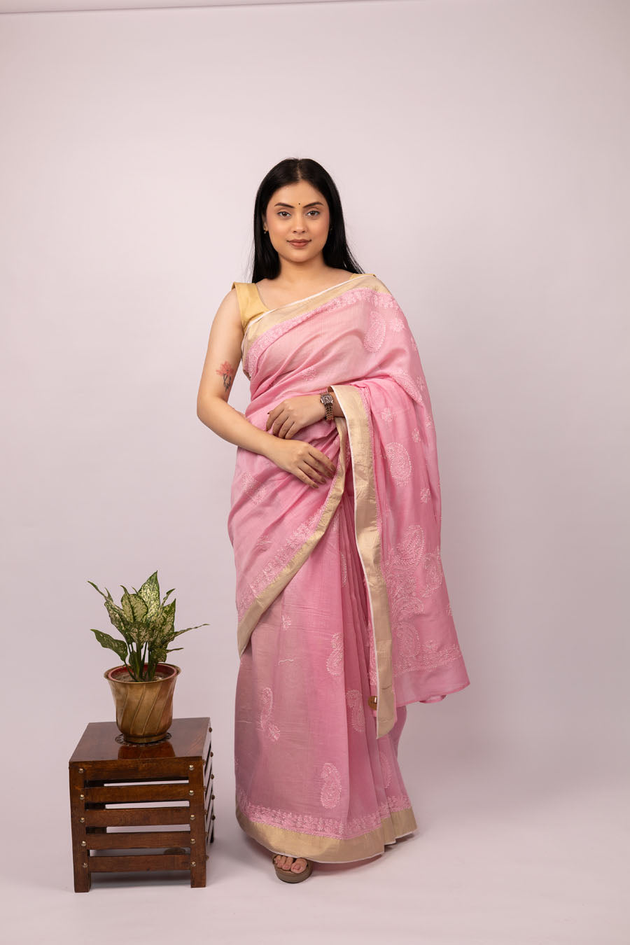 Woman wearing a pink saree with zari border and chikankari