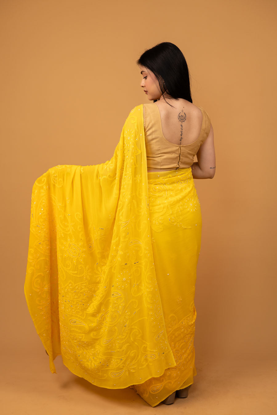 Back view of the drape of ellow georgette chikankari saree with embellishments