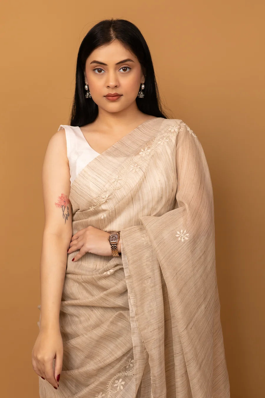 Woman wearing a beige saree with a plain background