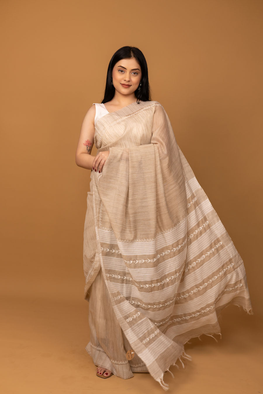Beige cotton saree showing elegant pallu with woven stripe border detail