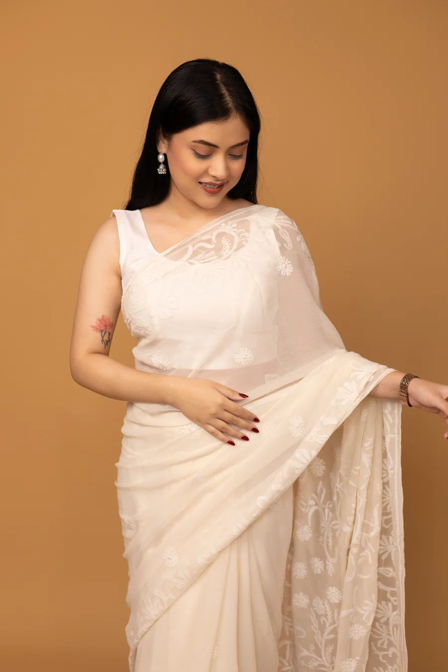 Woman wearing a white saree with a beige background