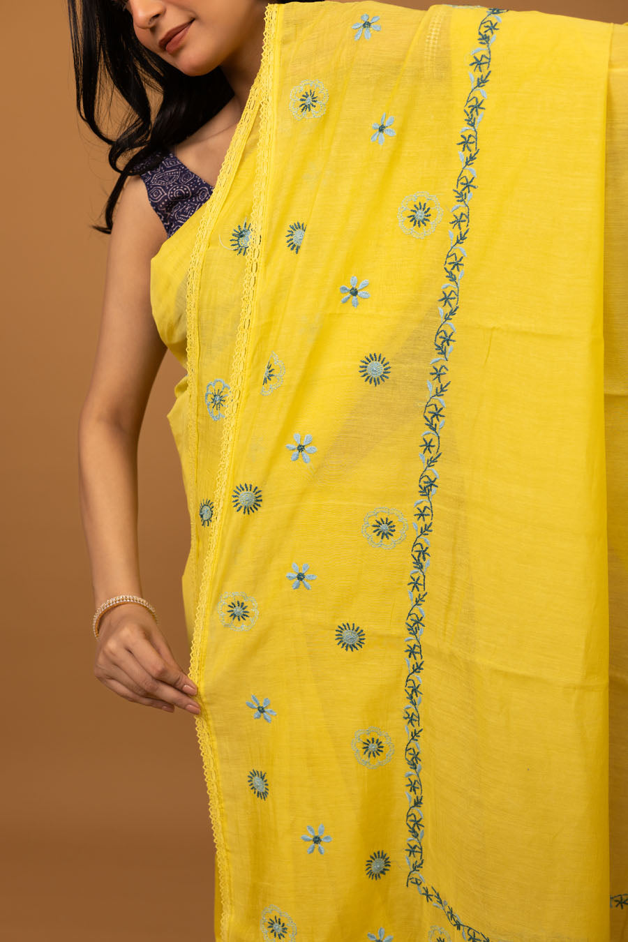 Close portrait showing texture of yellow chikankari saree with blue embroidery