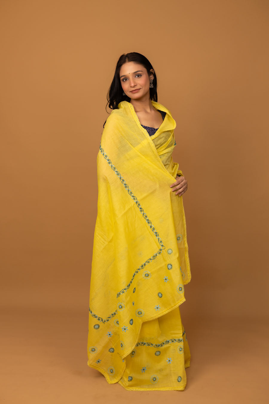 Woman wearing yellow chikankari saree with blue floral embroidery front drape view
